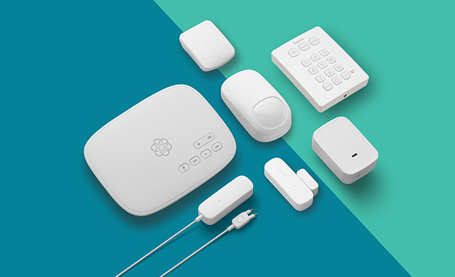 Ooma complete home security system with camera, sensors and all parts against a blue and green background.