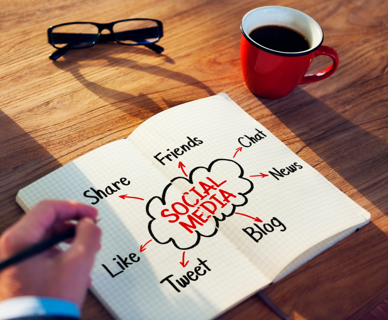 Hand holding a pen over a notebook with a diagram for social media ideas